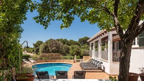 A swimming pool with lounge chairs, a pergola, and a view of trees and hills. - Villa Maite by Escape Home (Binibequer)