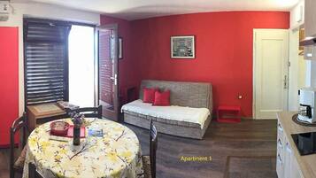 Un appartement compact comprenant un coin repas, un lit et une kitchenette.