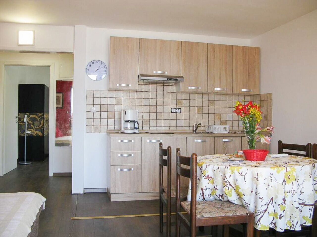 Eine kleine Küche mit Holzschränken, einer Kaffeemaschine und einem Esstisch mit Stühlen.