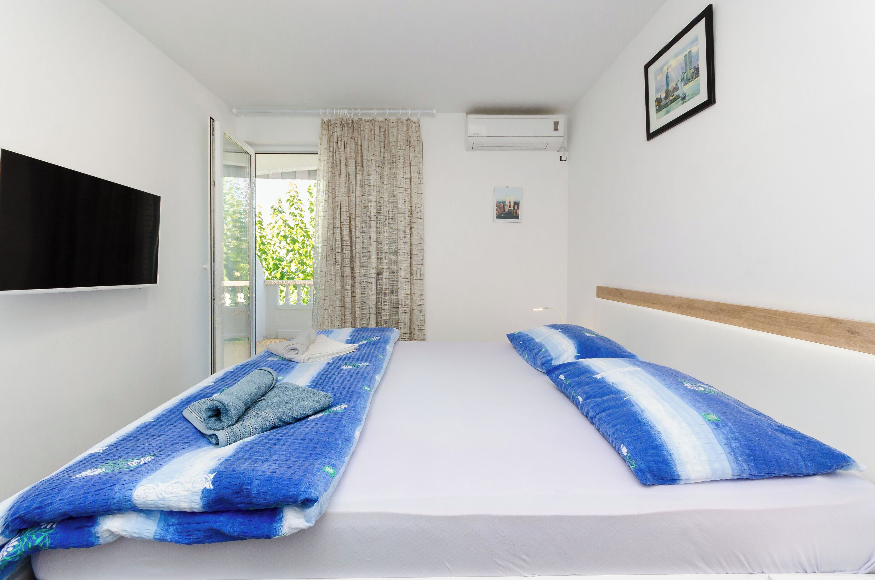Une chambre d’hôtel avec deux lits, un téléviseur fixé au mur et une fenêtre avec des rideaux.