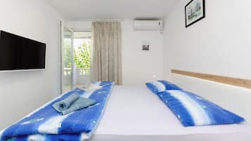Une chambre d’hôtel avec deux lits, un téléviseur fixé au mur et une fenêtre avec des rideaux.