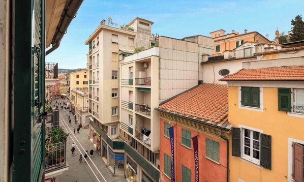 A narrow street lined with multi-story buildings, balconies, and a pedestrian walkway. - Maestrale 11, in the heart of the city of La Spezia, is a well-furnished open-space studio, perfect for couples. Located on the 4th floor of a historic building, without a lift, it will welcome you in its open space with a double bed, kitchenette, bathro (La Spezia)