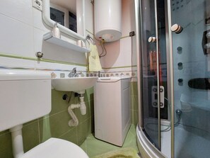 Casa de banho com lavatório, espelho, porta-toalhas e cabine de duche com parede de vidro.