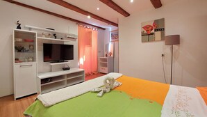 A bedroom with a bed, a TV, a wardrobe, and a painting. - Apartments Ineska (Crikvenica)