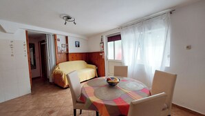 A dining area with a round table, chairs, and a yellow sofa in the background. - Apartments Ineska (Crikvenica)