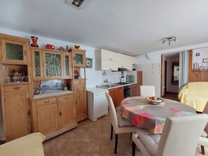 Una cocina compacta con armarios de madera, una mesa de comedor con sillas y un refrigerador pequeño.