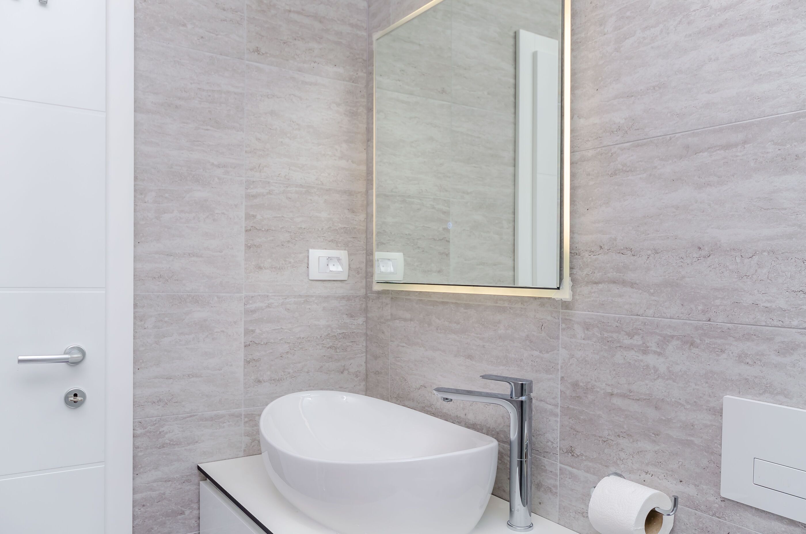 Une salle de bain moderne avec un lavabo blanc, un miroir et des toilettes.