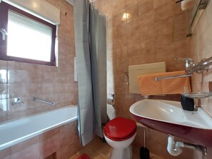 Ein Badezimmer mit Badewanne, Toilette, Waschbecken und Handtuchhalter.