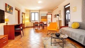 A well-lit living room with a sofa, a coffee table, and a dining area with chairs and a table. - Apartments Sinisa (Rovinj)