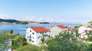 A coastal town with white buildings and red roofs, a marina, and a clear blue sky. - Apartments Zorka (Rab)