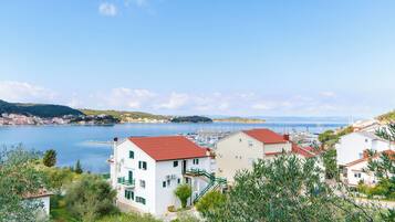 A coastal town with white buildings and red roofs, a marina, and a clear blue sky.
