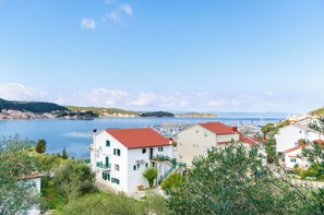 A coastal town with white buildings and red roofs, a marina, and a clear blue sky. - Apartments Zorka (Rab)