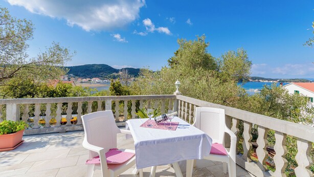 Une terrasse avec une table dressée pour deux personnes, offrant une vue panoramique sur la côte.