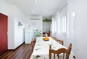 A dining area with a long table, chairs, and a fruit bowl. - Apartments Zorka (Rab)