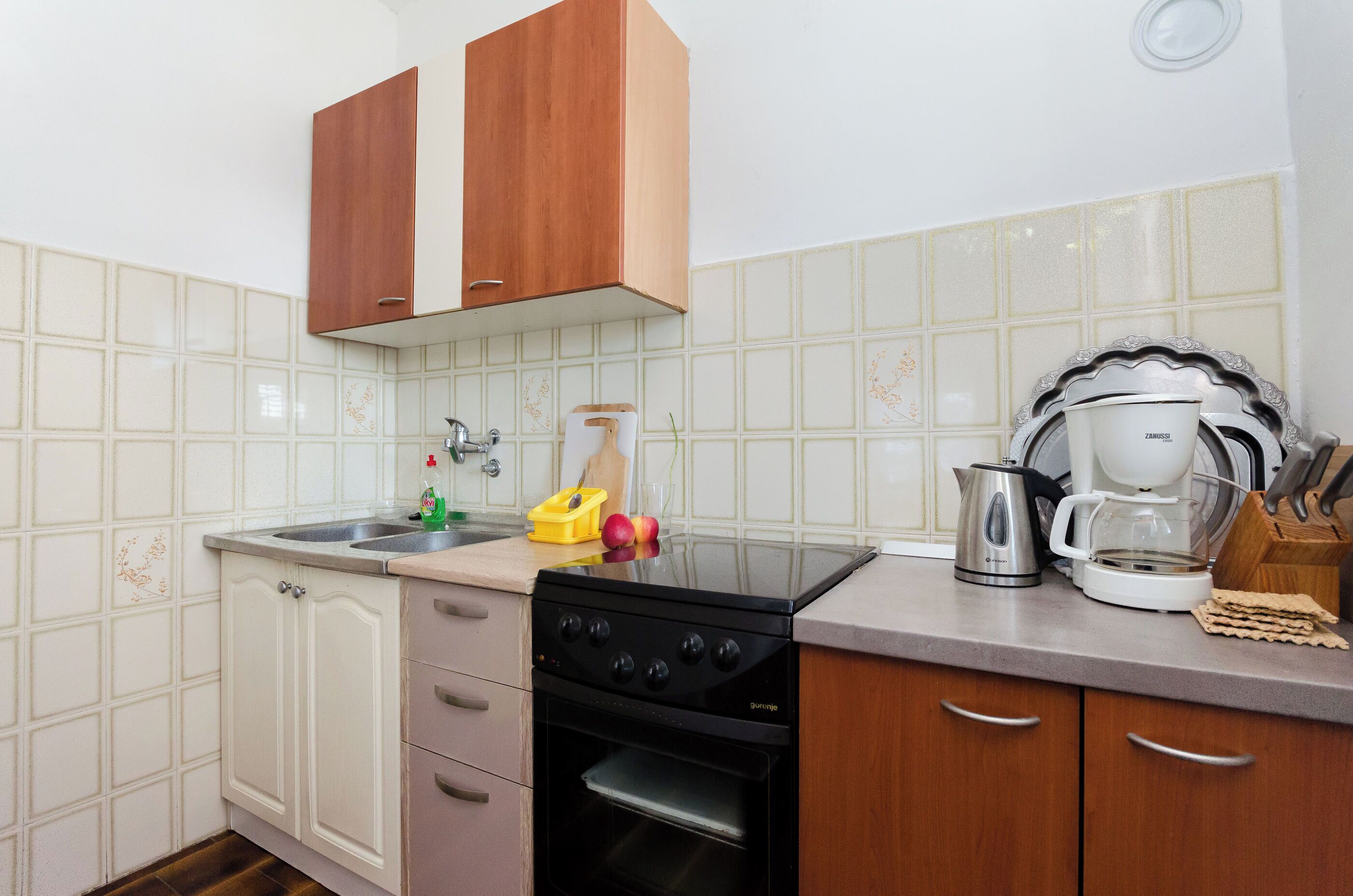 A kitchen with a stove, oven, sink, and wooden cabinets.