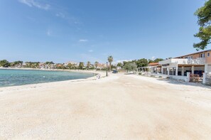 Ein Strandhaus mit Sandstrand, Pool und einem Gebäude, auf dem das Schild "ZODIAC" steht.