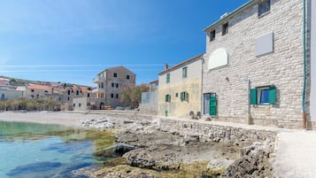 Un edificio costero con paredes de piedra, vista despejada al mar y un balcón.