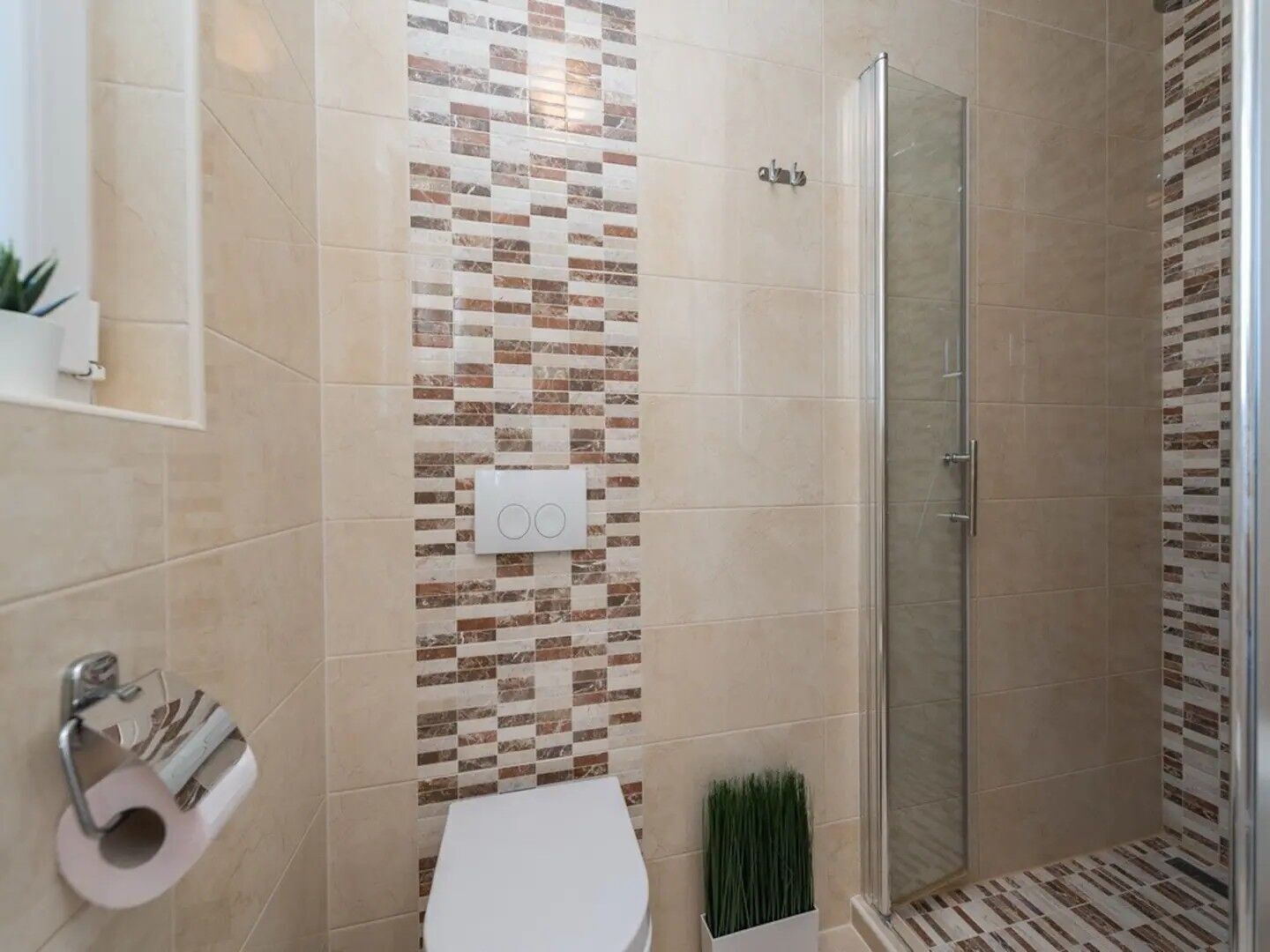 A bathroom with a shower, toilet, and a wall-mounted towel dispenser.