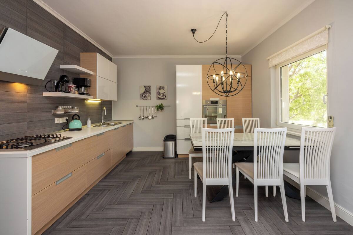 A modern kitchen with a built-in stove, white cabinets, and a herringbone-patterned floor.