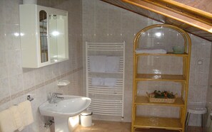 Ein Badezimmer mit Waschbecken, Spiegel, Handtuchhalter und Ablagefläche für Toilettenartikel.