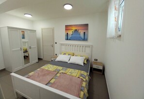 A bedroom with a bed, a wardrobe, a nightstand, and a painting on the wall. - Apartment Sabrina (Crikvenica)