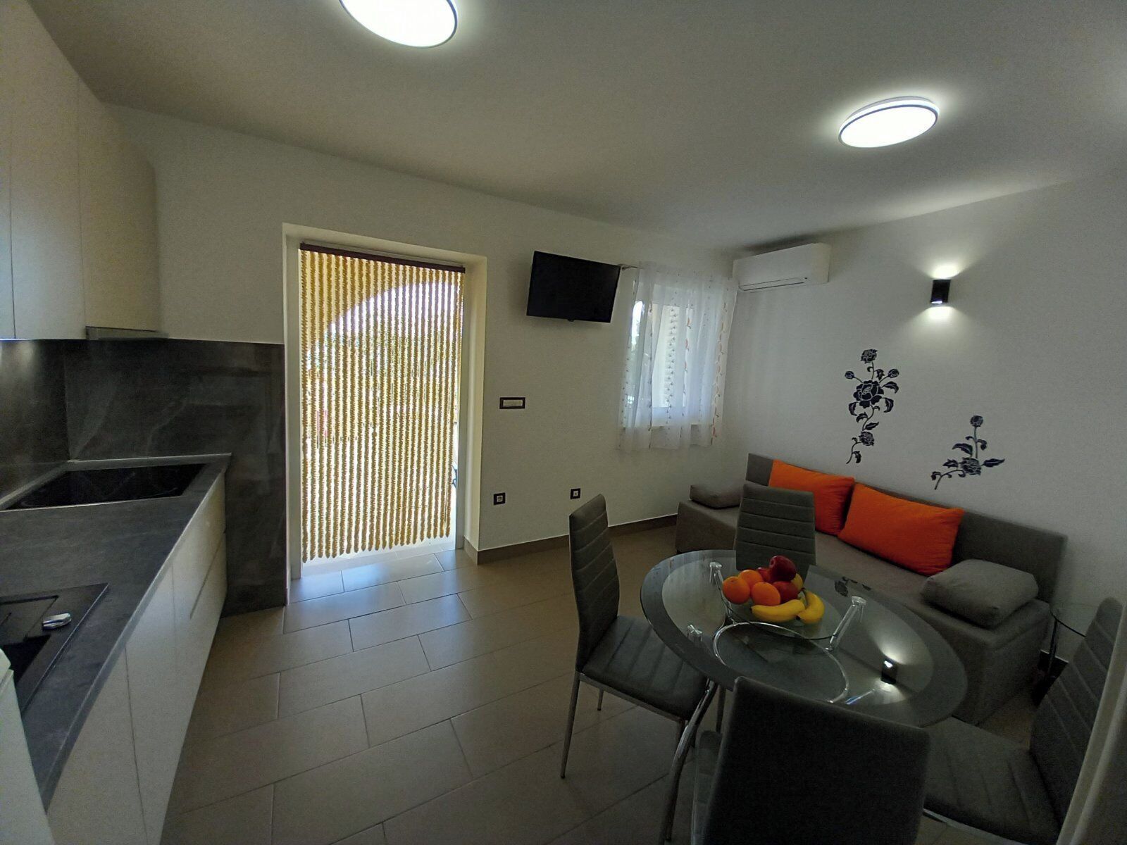 A compact living space with a kitchen, dining area, and a sofa with orange cushions.