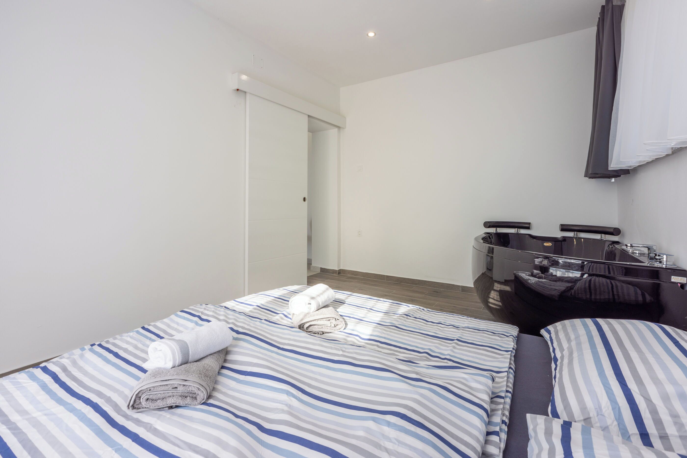 A hotel room with a bed, a bathroom, and a shower area.