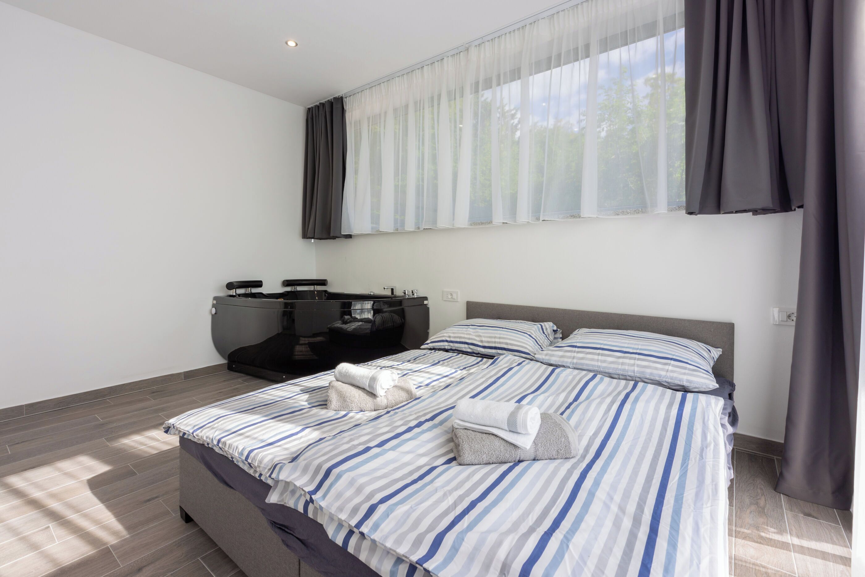 Quarto moderno com uma cama grande, uma escrivaninha e uma janela com cortinas.