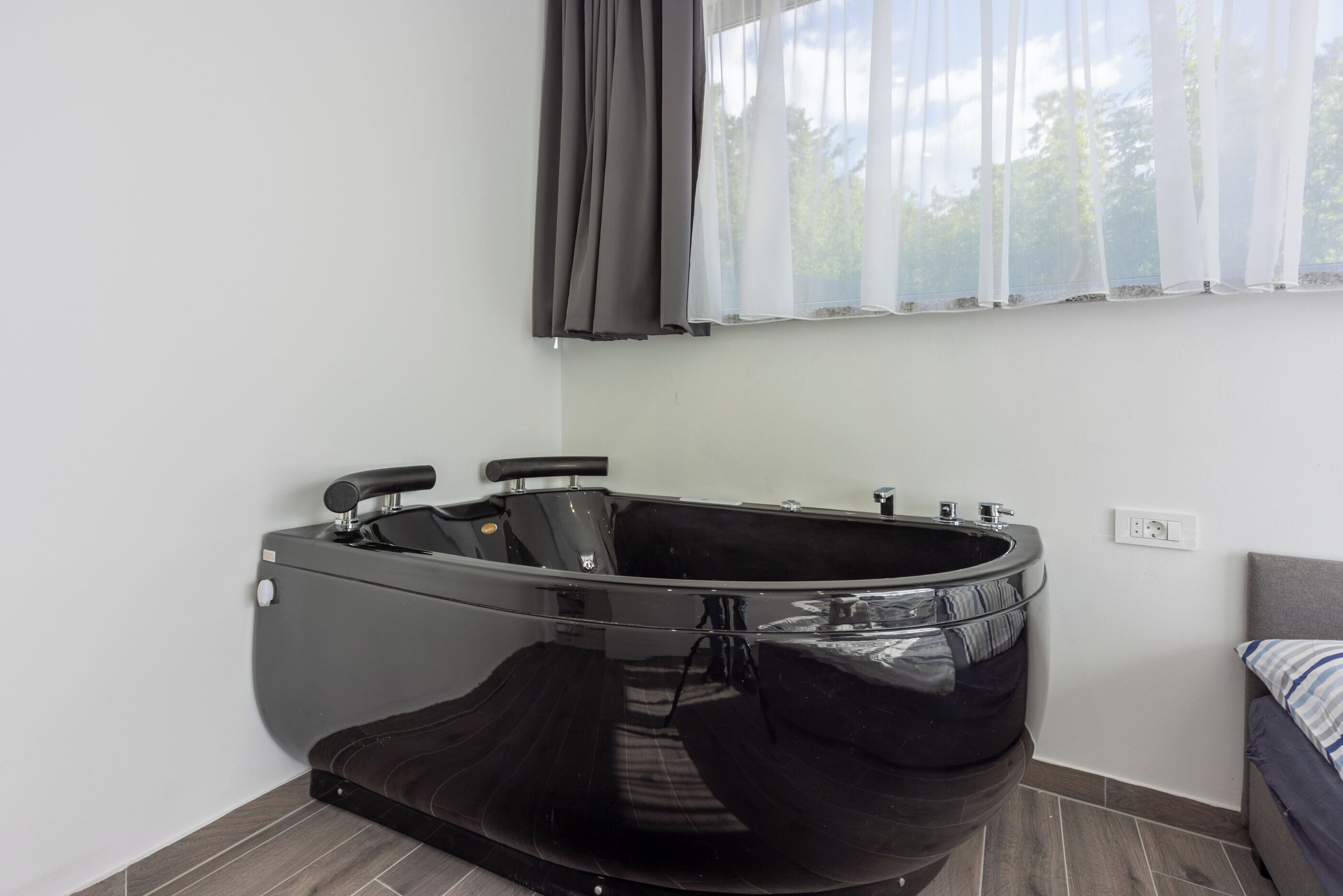 A modern bathroom with a black freestanding bathtub, a toilet, and a shower area.