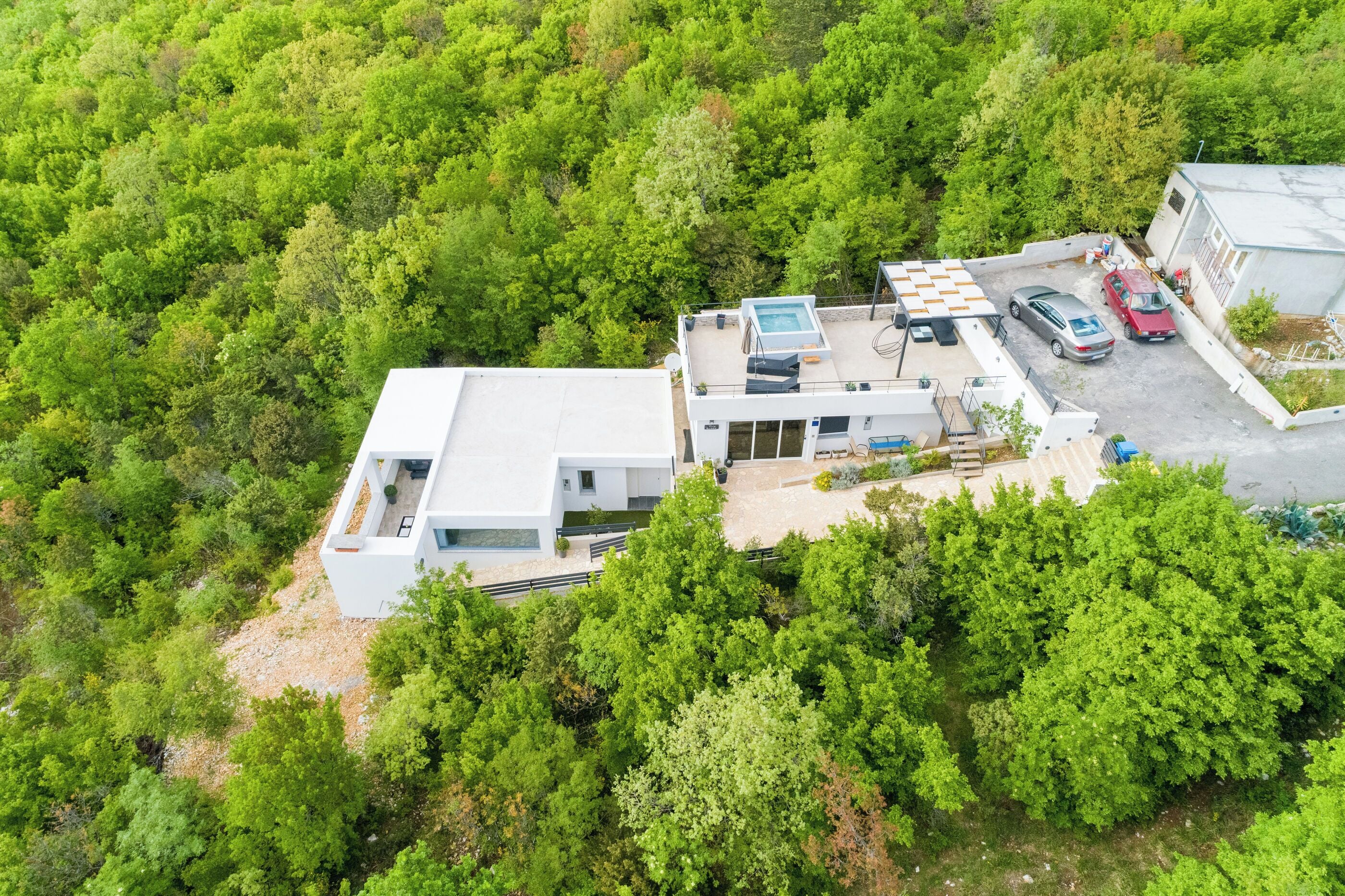 Vue aérienne d’une maison moderne dotée d’une piscine, d’un patio couvert et d’un espace de stationnement pour deux voitures.