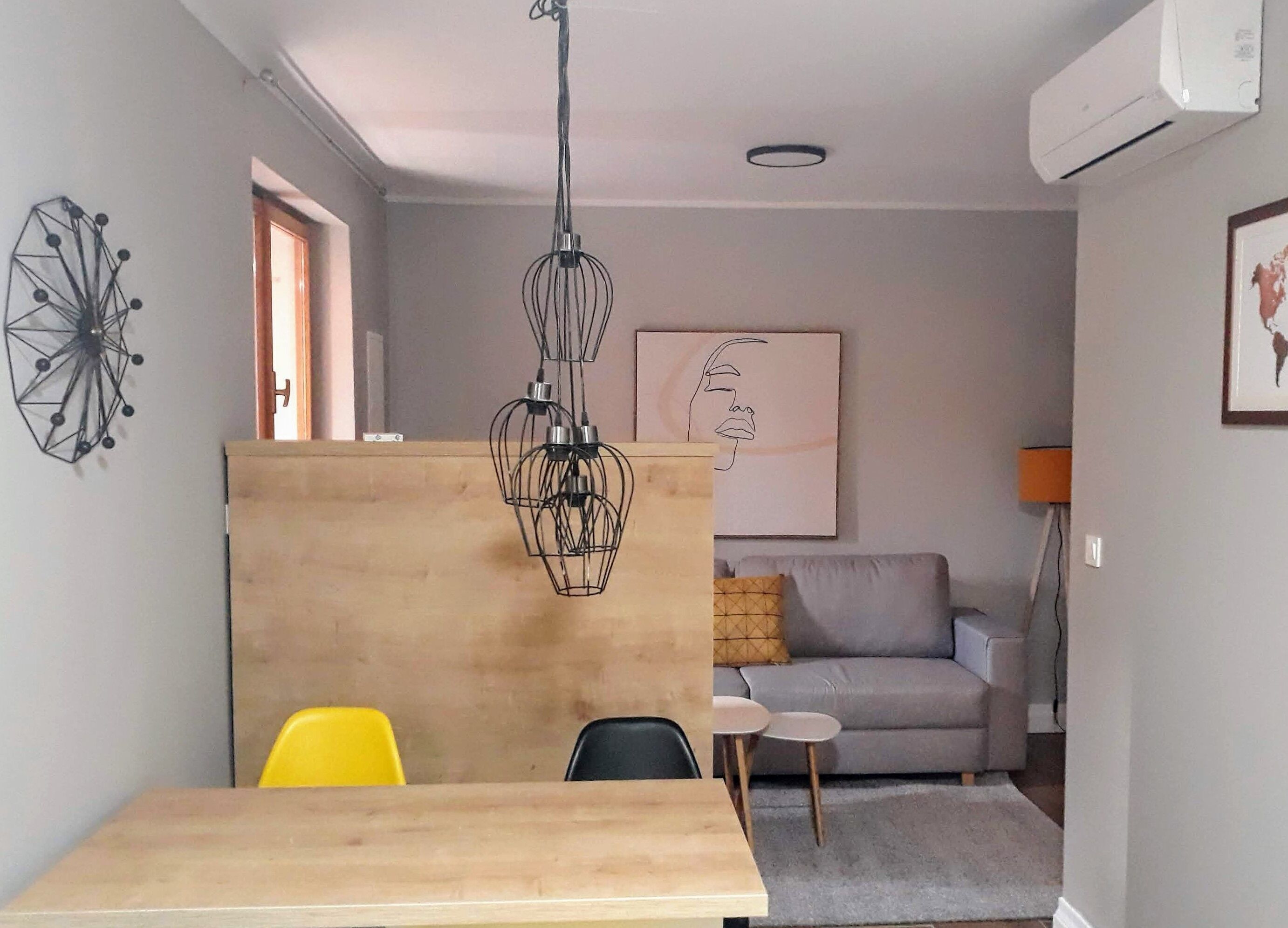 A compact living space with a wooden partition, a dining table, a sofa, and a small side table.