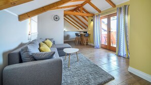 Un salon moderne avec un canapé d’angle gris, une petite table blanche et un plafond en bois.