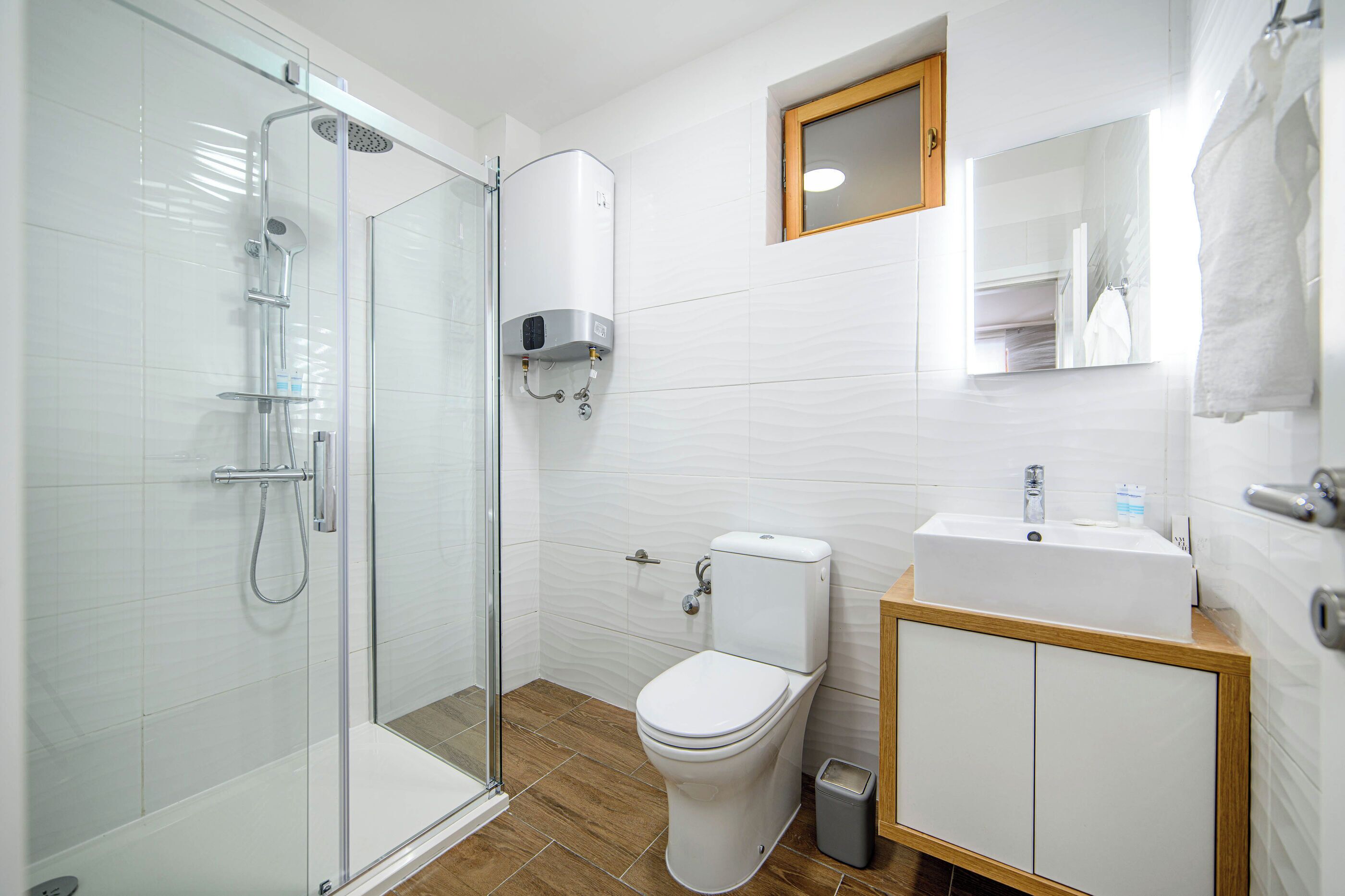 Une salle de bain moderne avec une douche à parois de verre, des toilettes et un lavabo doté d’un plan de travail en bois.