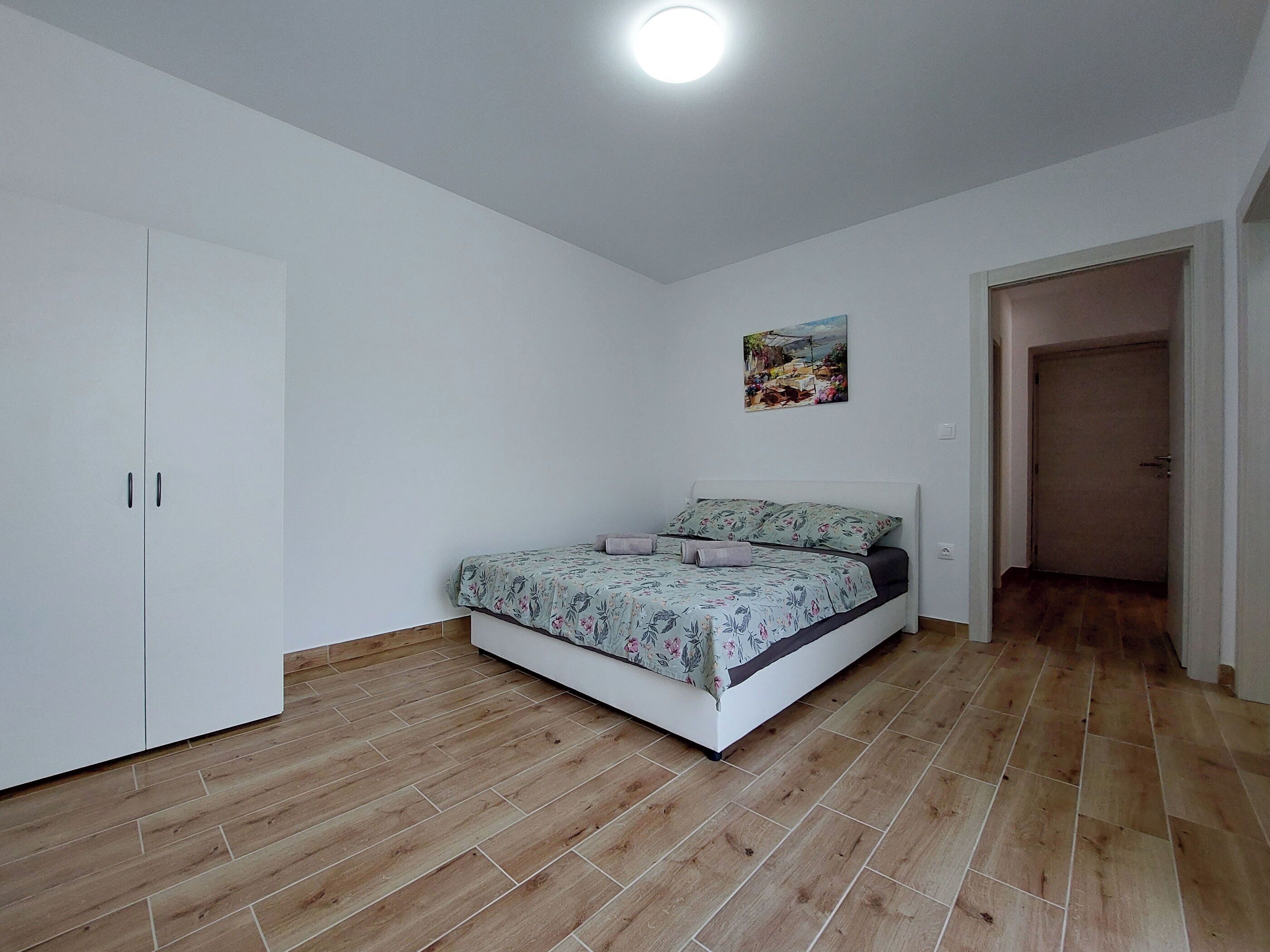 Une chambre à coucher avec un lit, une armoire et un tableau au mur.