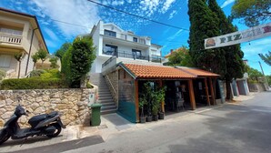 Un edificio moderno con facciata in pietra, un'area salotto esterna coperta e un cartello per una pizzeria.