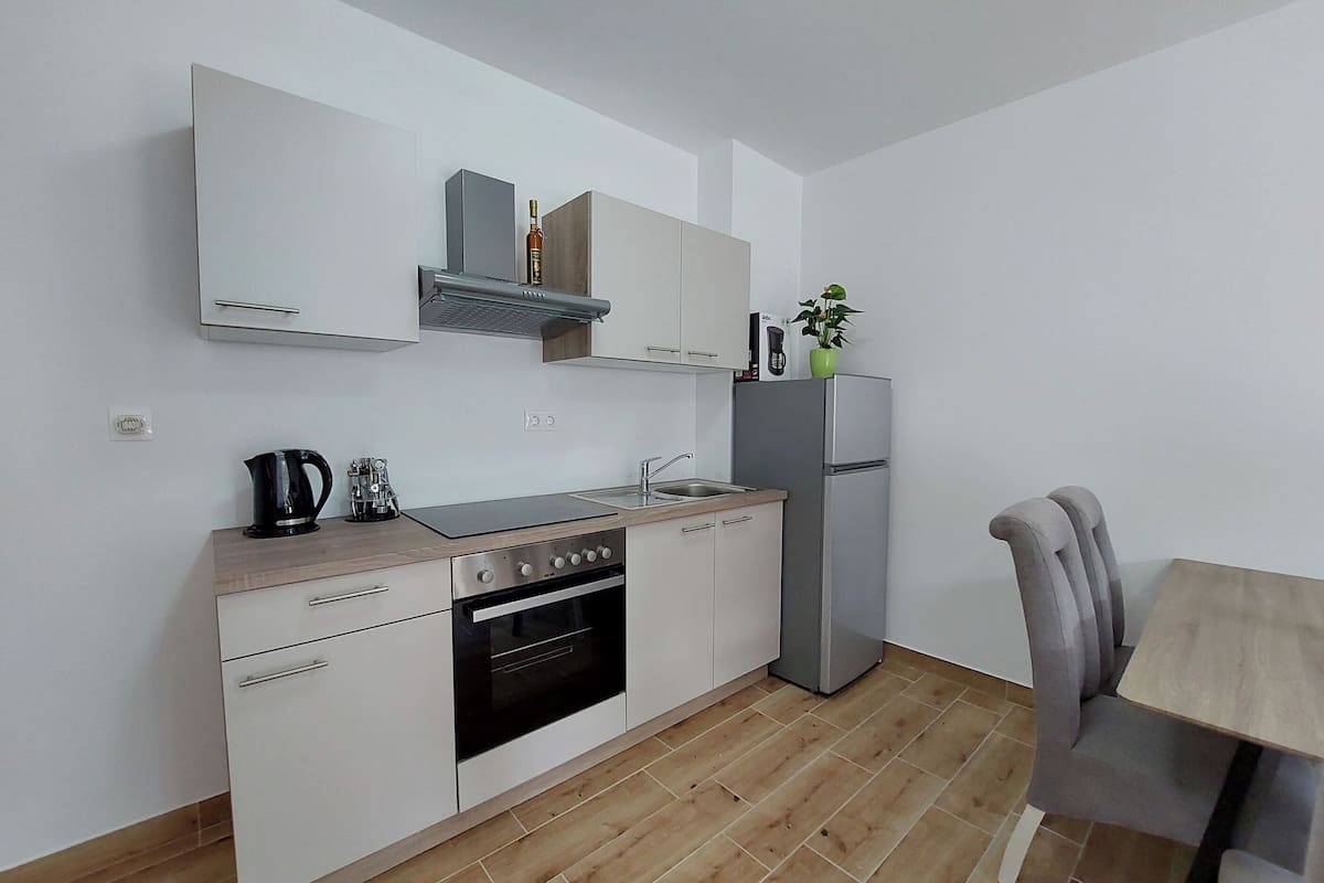 Een moderne keuken met witte kasten, een roestvrijstalen koelkast, een inbouwoven en een koffiezetapparaat.