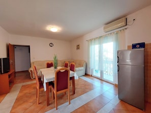 A compact living space with a dining area, a sofa, a TV, and a refrigerator. - Apartments Irena (Crikvenica)