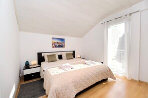 A bedroom with a bed, nightstand, lamp, and a painting on the wall. - Apartments Ria Vodice (Vodice)