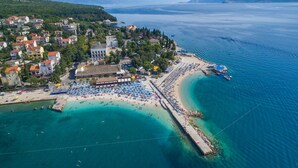 Luftaufnahme einer Küstenstadt mit Strand, einem Hotel und einer Seebrücke.