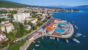 Eine Luftaufnahme einer Küstenstadt mit einem Yachthafen, Gebäuden und einem großen Hotel.