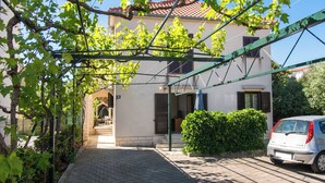 Un vialetto lastricato conduce a un edificio con una pergola in metallo verde.