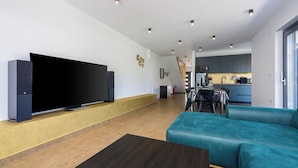 A modern living room with a large flat-screen TV, a teal sofa, and a wooden coffee table. - House Neptunia (Medulin)
