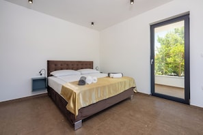 A bedroom with a bed, a nightstand, and a sliding glass door to an outdoor area. - House Neptunia (Medulin)