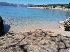 A clear view of a rocky shoreline with calm water and distant mountains. - Apartment Vesna (Krk)