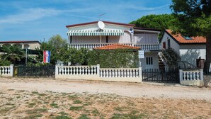 Una casa a due piani con un balcone, un'antenna parabolica e una bandiera.