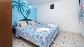 Una camera da letto con un letto, un comodino, un muro decorato con un murale di palme e una piccola foto incorniciata appesa al muro.