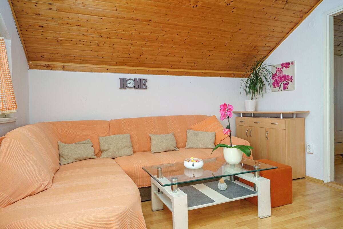 A modern living room with a wooden ceiling, a sofa, a glass coffee table, and a cabinet.