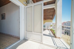 Une pièce dotée d’une porte coulissante donnant sur un balcon avec vue sur les immeubles voisins.