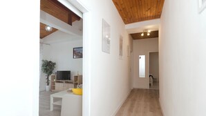 Un interior moderno con techo de madera, un sofá blanco, un televisor y una planta.