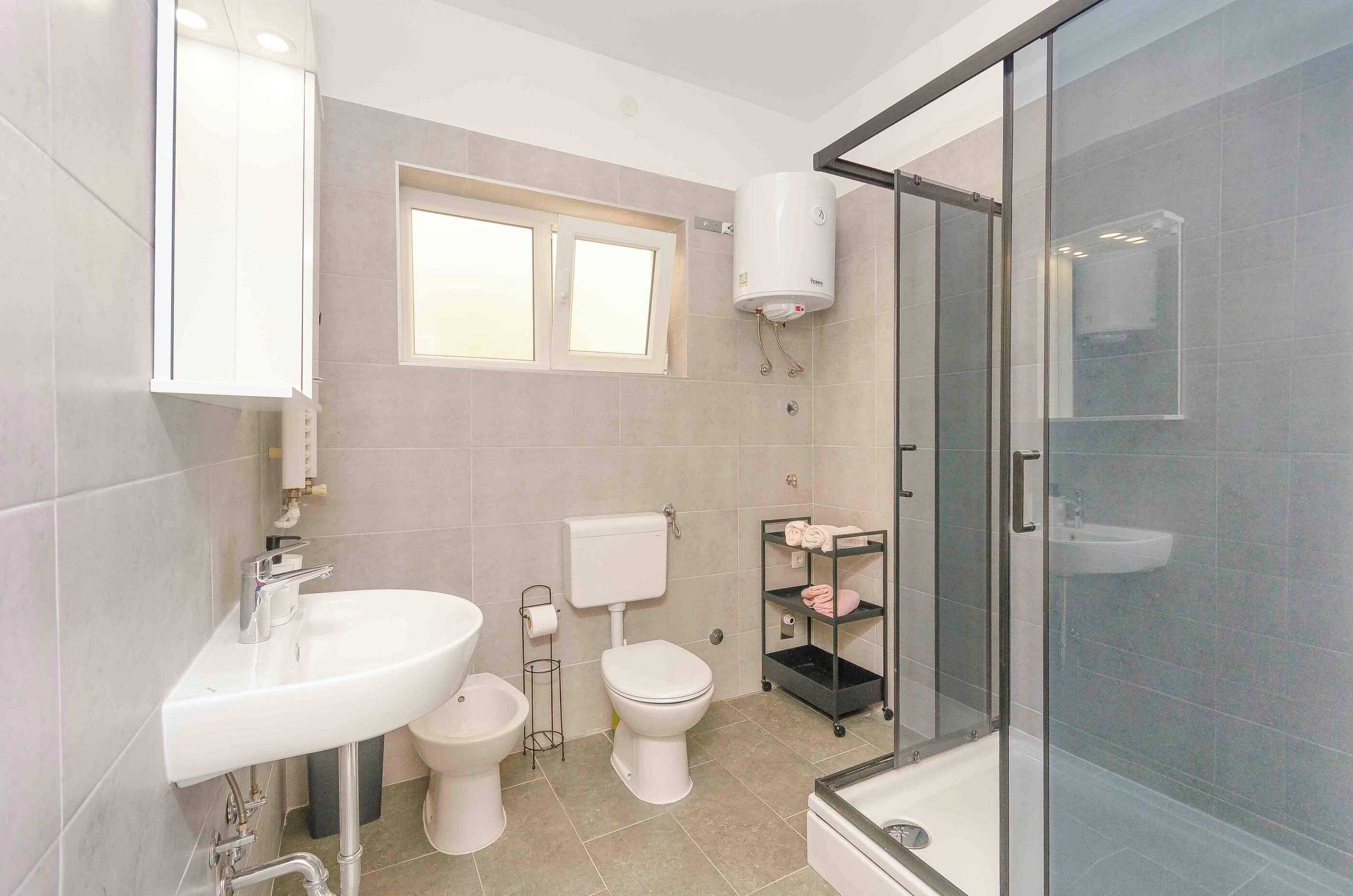 A modern bathroom with a toilet, sink, and shower.